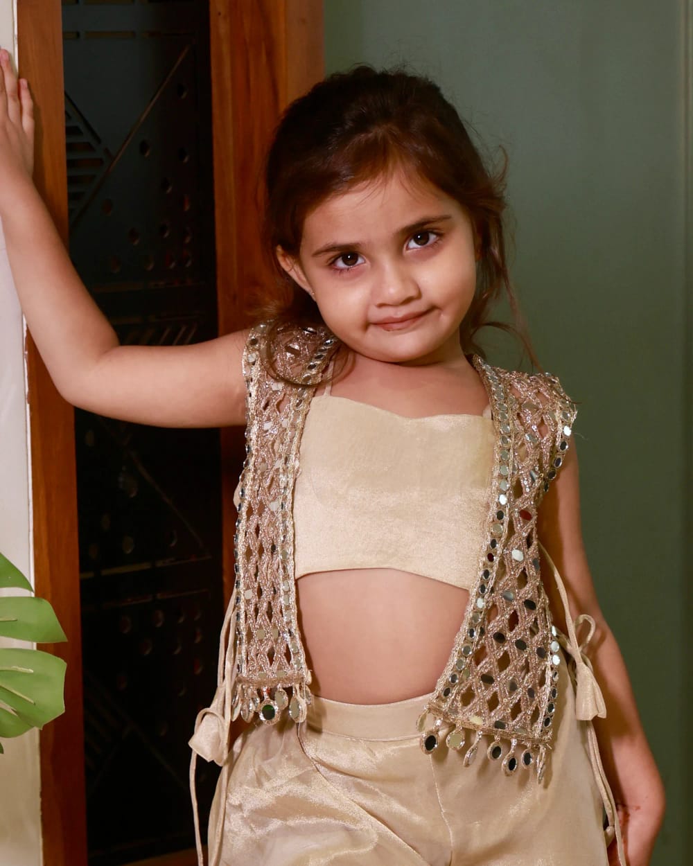 The mirror-work waistcoat worn open over the gold bandeau