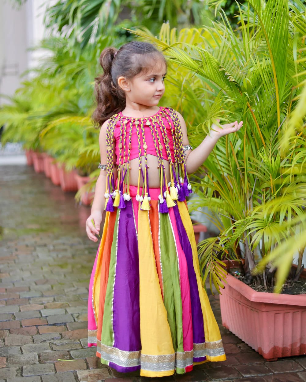 A girl in the multicoloured chaniya and tasselled pink blouse, one hand open