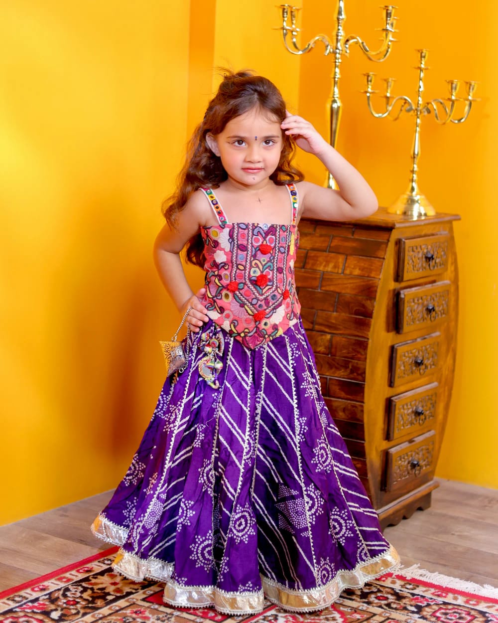 A girl in a purple bandhani ghagra with an embroidered bodice and silver gota hem