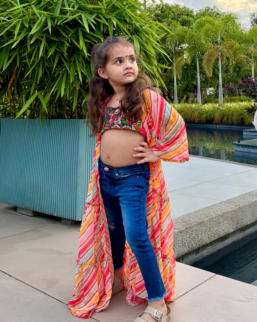 A girl in the long leheriya shrug, worn open over a mirror-work crop top and jeans